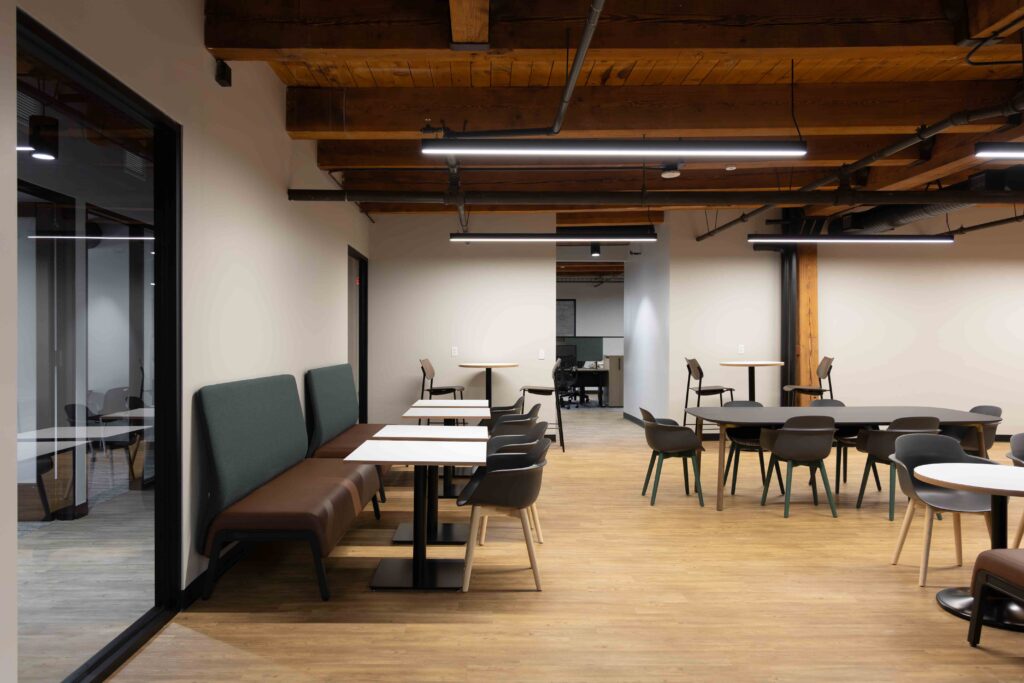 Breakroom in Branigan’s Milwaukee office with booth seating, round and rectangular tables, and modern chairs beneath exposed timber ceilings