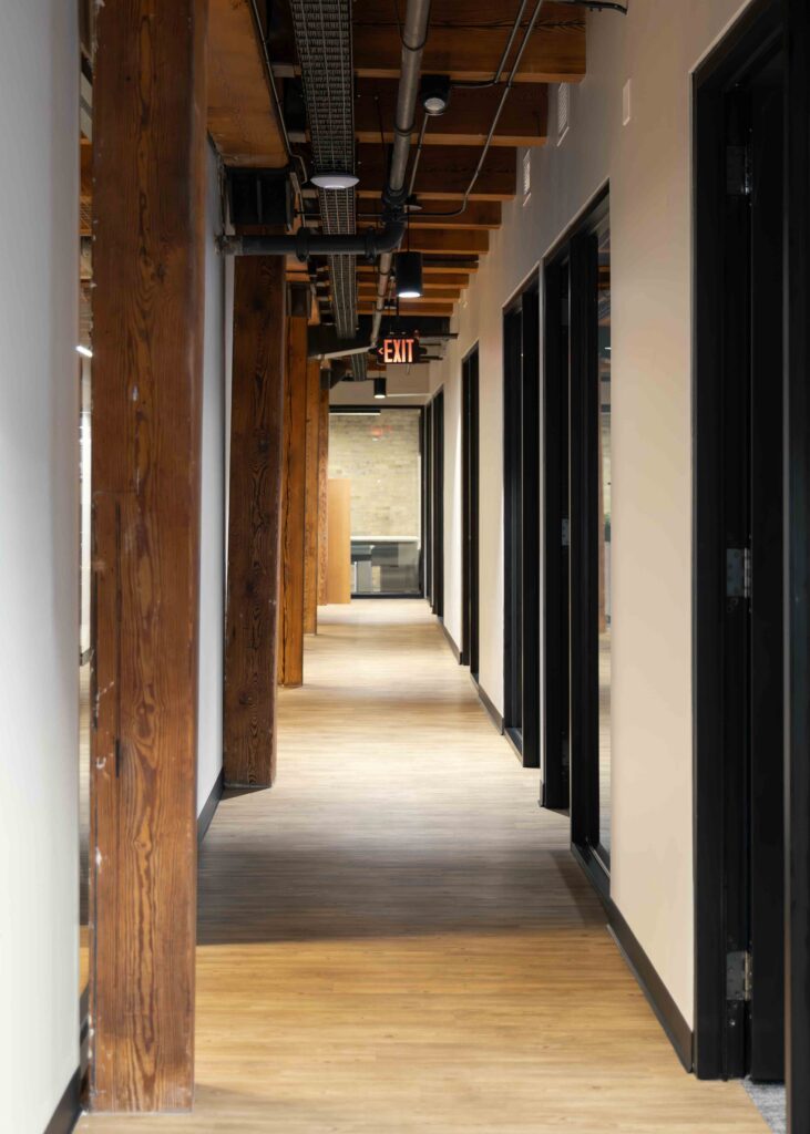 Hallway in Branigan's Milwaukee office featuring black framed glass doors and timber beams