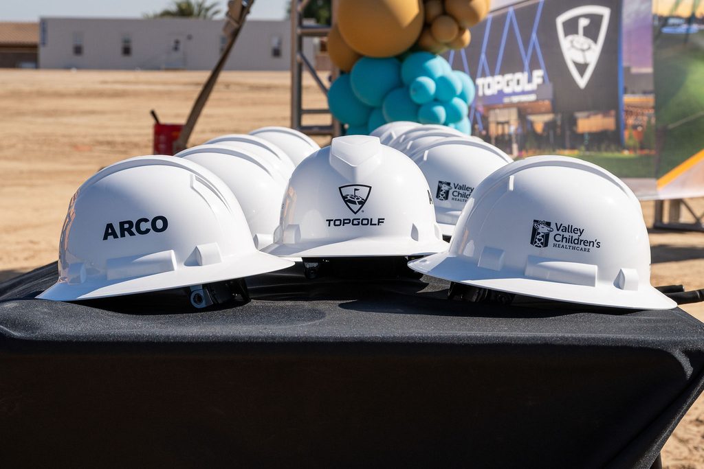 Hardhats with the 3 partners logos, Topgolf, ARCO and Valley Children's Hospital.